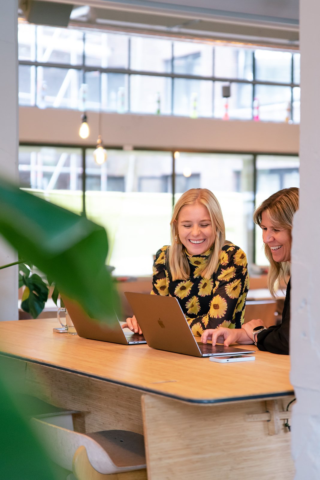 Twee lachende medewerkers van Great Place To Work werken achter laptop